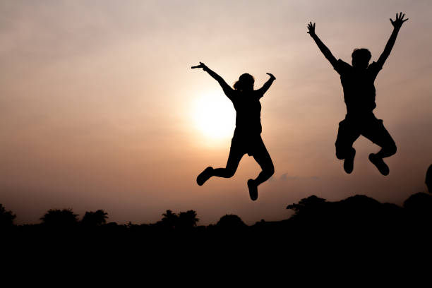 istock Silhouette of two young adults jumping cheerfully 1214926218