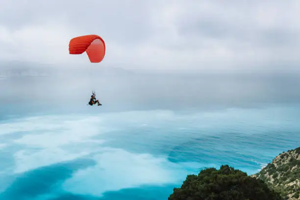 Photo of Paraglider against blue sea with foggy clouds. Kefalonia island, Greece. recreation hobby activity.