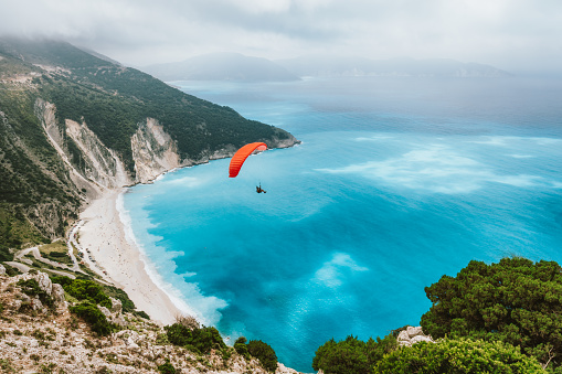 Actividad de la temporada de verano. Glider volando sobre la hermosa playa de Myrtos. Isla Cefalonia, Grecia. Increíbles colores de agua y costa de montaña photo