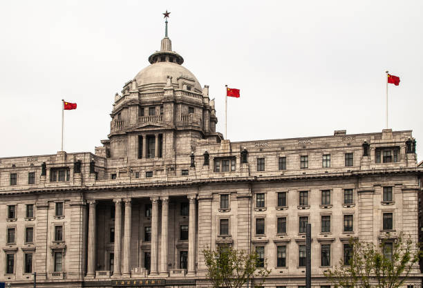 Shanghai, China - May 4, 2010: Brown stone historic HSBC building with dome, and star on top. Red Chinese flags under silver sky.