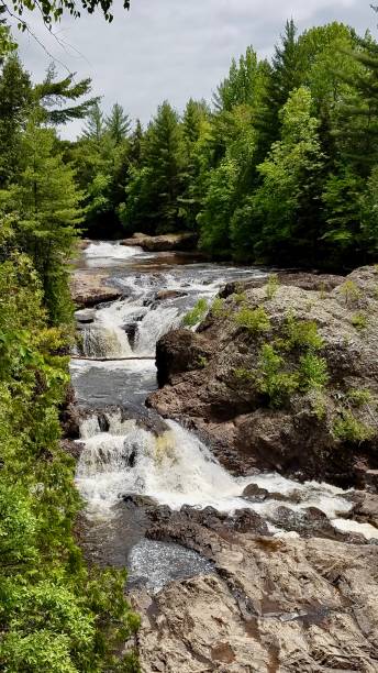 istock Summer waterfall with green trees in the background in a verticle format 1214929998