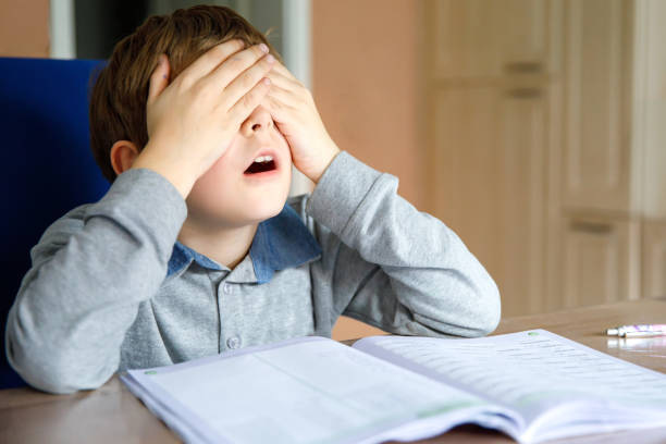 istock Upset school kid boy making homework during quarantine time from corona pandemic disease. Crying and sad boy frustrating staying at home. 1214931426