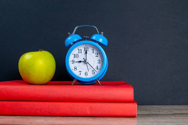istock Blue watch and green apple stand on red books 1214932173