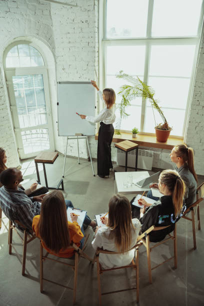 istock Female caucasian speaker giving presentation in hall at university or business centre workshop 1214932183