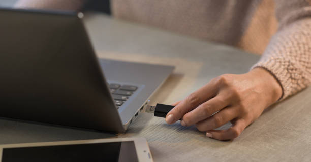 istock Woman plugging a USB flash drive into her laptop 1214933524