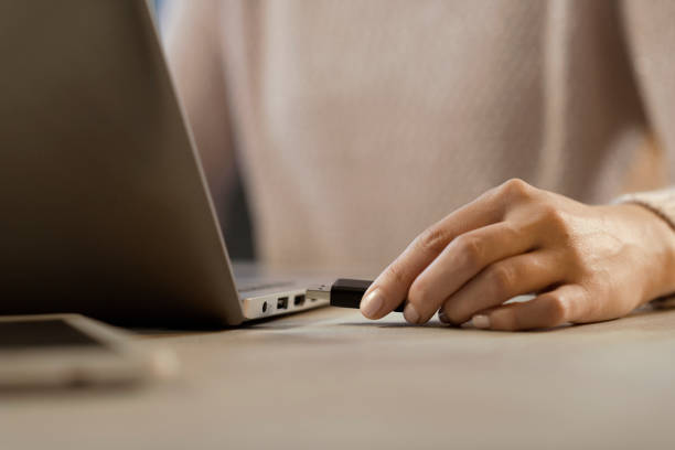 istock Woman plugging a USB flash drive into her laptop 1214933600