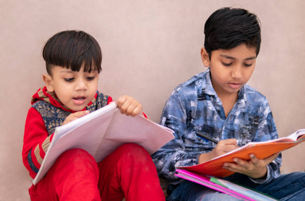 kleine brüder studieren zusammen. - reading and writing little boys reading asian ethnicity stock-fotos und bilder