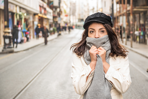 Young beautiful woman covering face with woolen scarf.