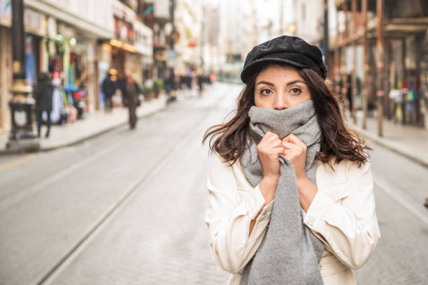 Young beautiful woman covering face with woolen scarf. stock photo