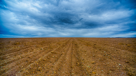 A ploughed piece of land with a dramatic blue sky above