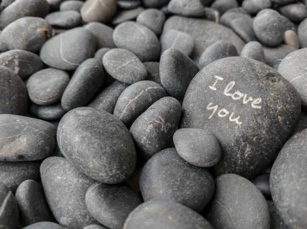 black and rounded pebbles with the phrase I LOVE YOU engraved on one of them