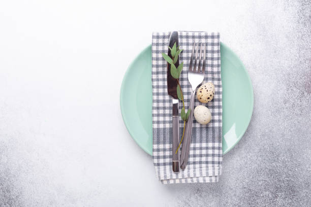 istock Easter table setting. Empty mint and white plates, linen napkin, eucalyptus leaves and quail eggs on stone background 1214952795