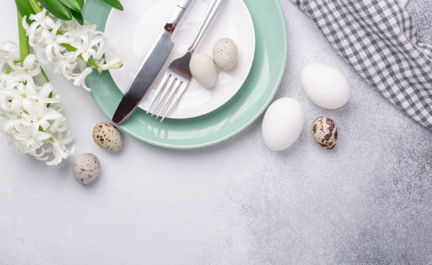 istock Beautiful Easter table setting in Scandinavian style. Green mint plate, eggs and silver cutlery on modern concrete background with hyacinth. Copy space. Top view 1214952869