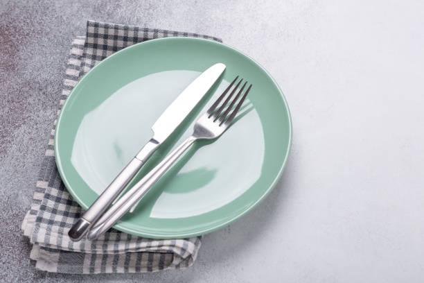 istock Empty mint plate, linen napkin, knife and fork on stone background Copy space Top view 1214952892