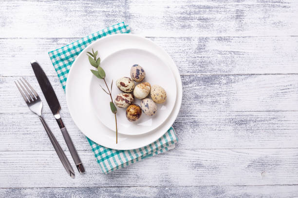 istock White plate with quail eggs and cutlery on wooden background. Easter composition. Copy space. Top view 1214953430