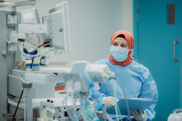 Asian female nurse monitoring and note down report during surgery at operating theatre in hospital stock photo