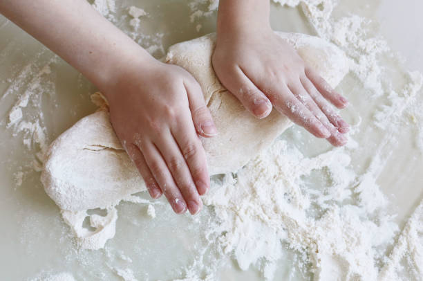 istock Making dough from flour. The child kneads the dough closeup 1214954964