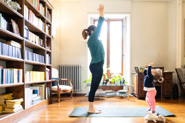 mother and daughter doing yoga together stock photo