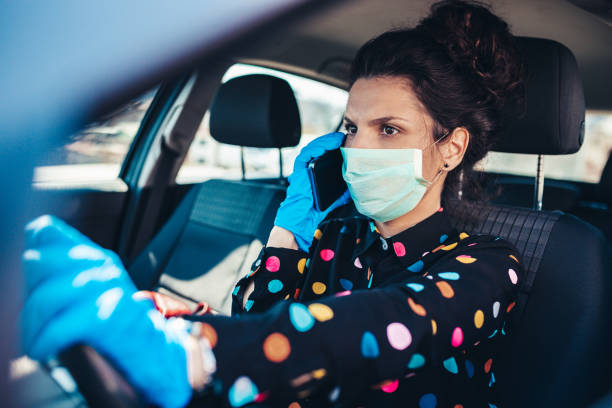istock Woman driving car while wearing protective mask 1214960598