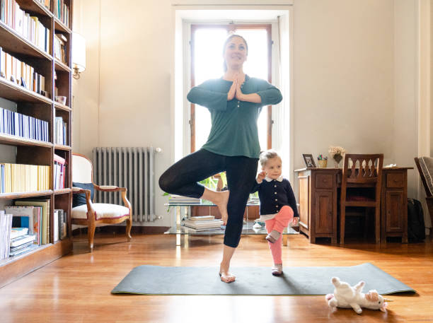 mother and daughter doing yoga together stock photo