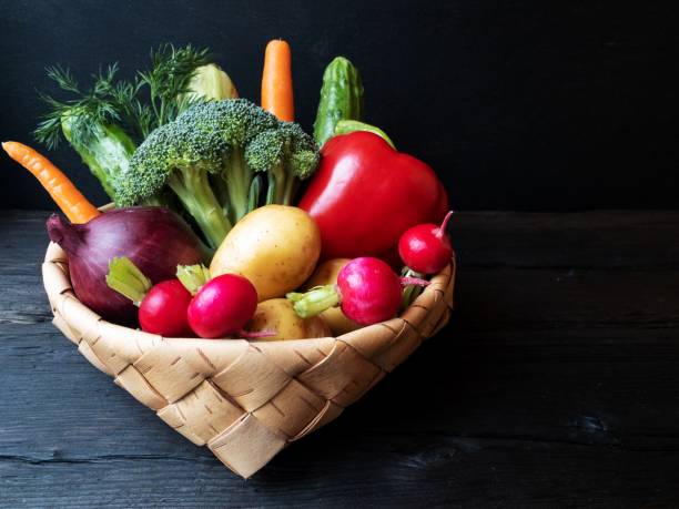 黒い背景に籐のバスケットに新鮮な野菜 - plum fruit basket wicker ストックフォトと画像