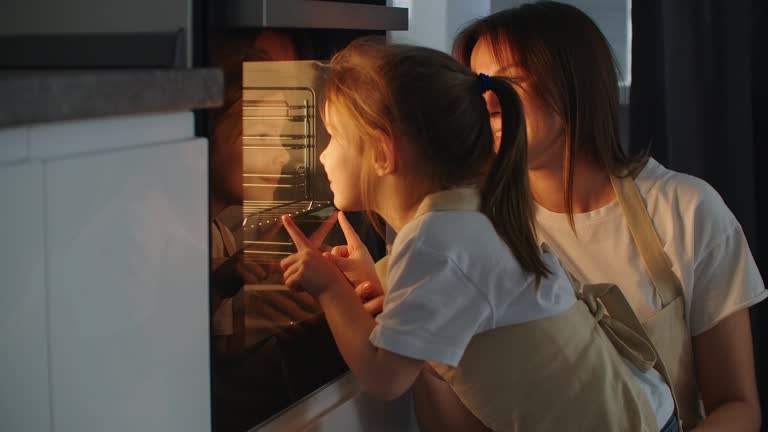 Mother Mother and daughter watch as a pie is prepared in the oven. Happy childhood. Make homemade pizza together