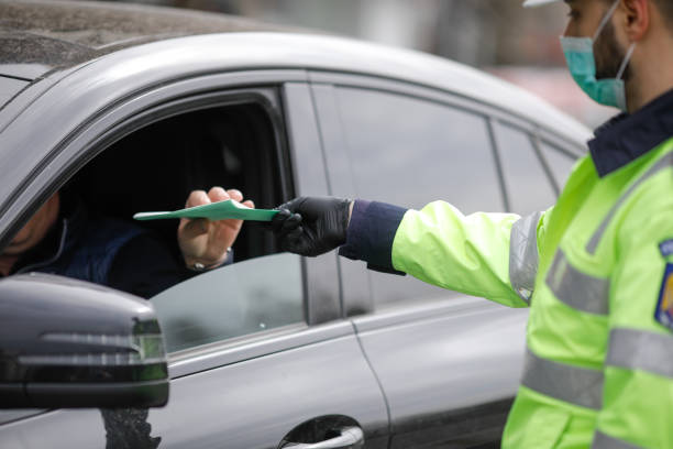 un policier roumain s’arrête sur une voiture pour vérifier les papiers du conducteur. - curfew photos et images de collection