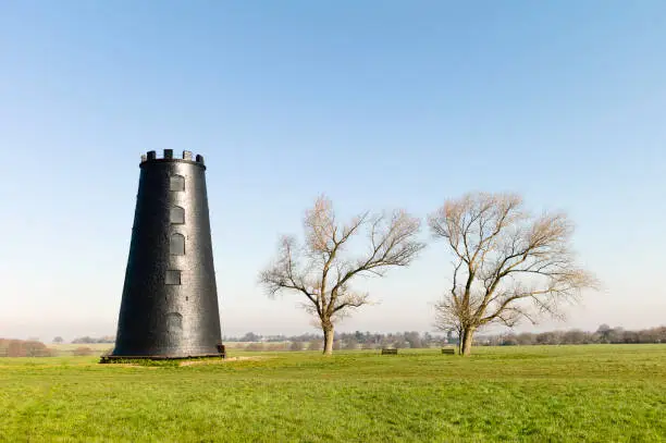 Black Mill, a local landmark, flanked by leafless trees under blue sky in the Westwood in early spring near Beverley, Yorkshire, UK.