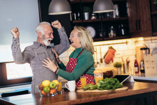 istock Senior couple is dancing and smiling while cooking together in kitchen 1214964773