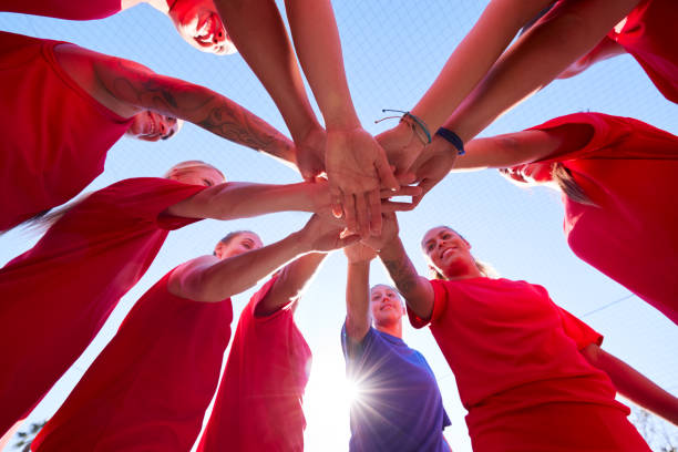 istock Low Angle View Of Manager Joining Hands With Womens Soccer Team During Pep Talk Before Match 1214966499