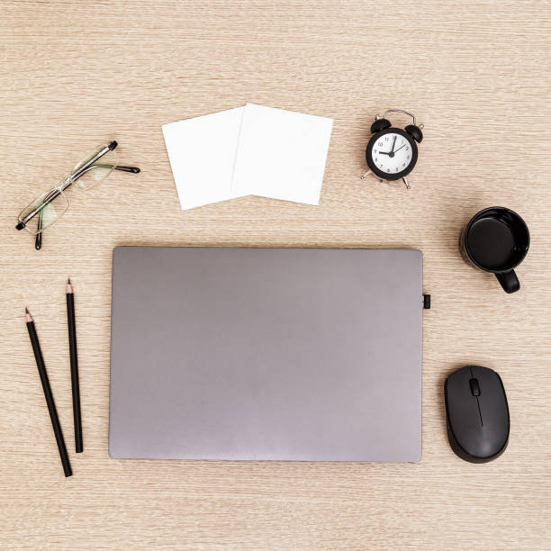 istock Desktop for student or freelancer. Working space. Workplace with grey modern laptop, cup of coffee, glasses and clock for time control on light table. Flat lay. 1214966812