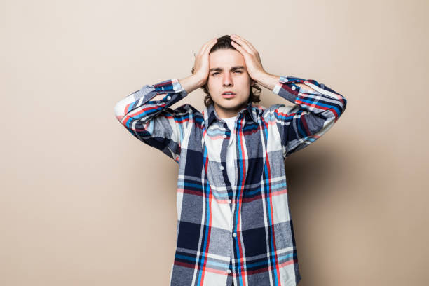 istock Young handsome man with hands on head on beige background 1214969354