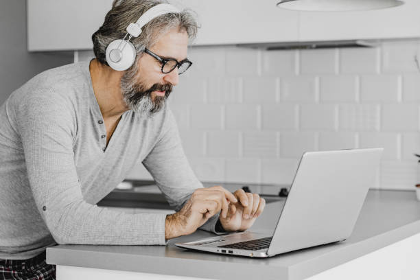 Mature modern man using laptop at home