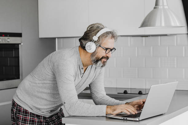 istock Mature modern man using laptop at home 1214971858