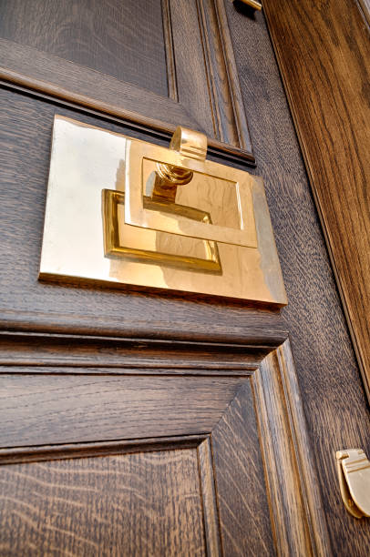istock A brass handle, knocker and paneling on wooden grained door 1214972471