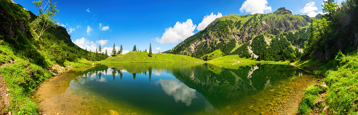 Gorgeous lake surrounded by mountains, with deep blue sunny sky and the amazing scenery reflected in the clear water