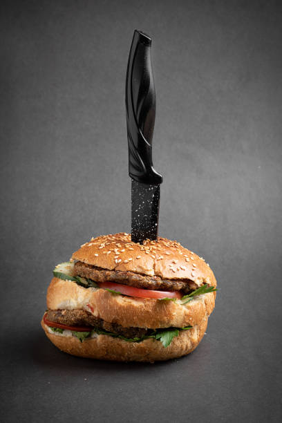 istock Big Hamburger pinned with knife on grey paper 1214975540