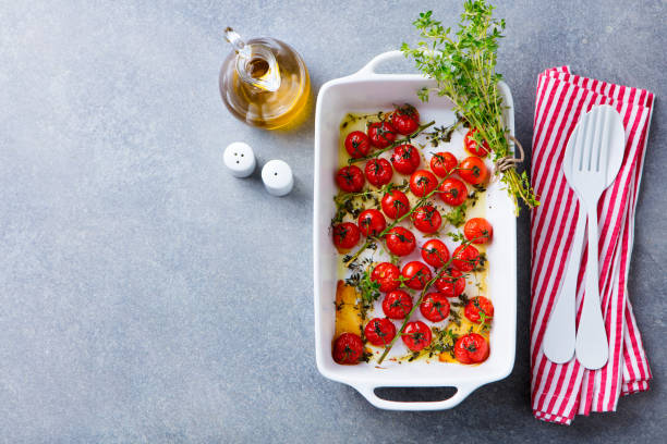 istock Roasted cherry tomatoes with herbs in baking dish. Grey background. Copy space. Top view. 1214976101