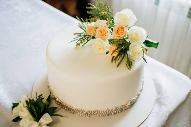 istock Wedding cake covered with white icing and orange flowers 1214977249