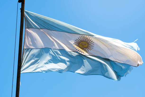 istock Argentina national flag waving on pole against sunny blue sky background 1214977313
