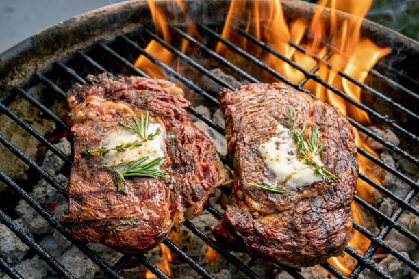 two delicious thick juicy ribeye steaks on a flaming grill - surf and turf prepared shrimp seafood steak imagens e fotografias de stock