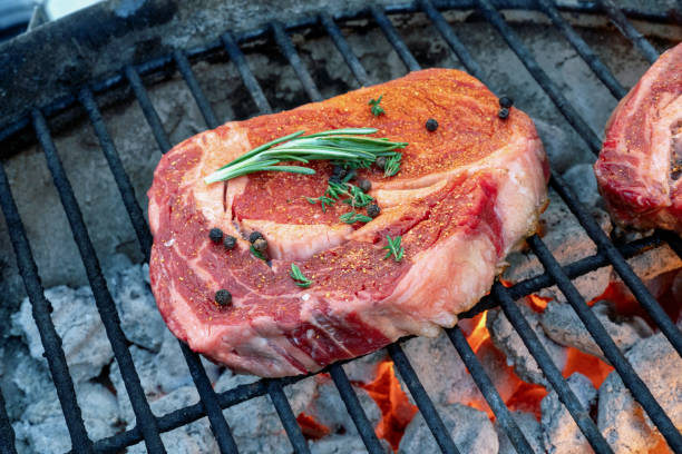 two raw ribeye steaks on a hot charcoal grill - surf and turf prepared shrimp seafood steak imagens e fotografias de stock