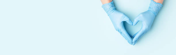 Hand in medical gloves. Doctor's hands in medical gloves in shape of heart on blue background. Banner for website with copy space. beauty clinic stock pictures, royalty-free photos & images