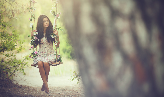 beautiful woman sitting on ivy swing in forest