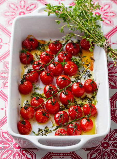 istock Roasted cherry tomatoes with herbs in baking dish. Close up. 1214980812