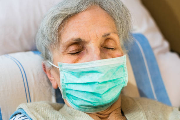 istock elderly woman lying in bed with a face mask 1214981418