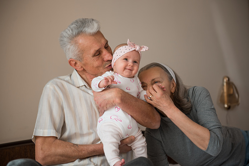 Happy girl with her's grandparents. Grandfather kissing her