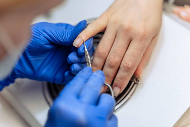 le processus de plan rapproché du maître féminin professionnel de manucure au salon de beauté enlève la peau sèche de cuticule près des ongles la coupant avec des ciseaux. concept de soins corporels. ongles de fichier esthéticienne à un client - nail file acrylic painting fingernail manicure photos et images de collection