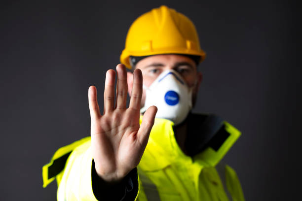 young engineer in medical mask making stop sign. health and safety concept - corporate business manager manual worker architect imagens e fotografias de stock