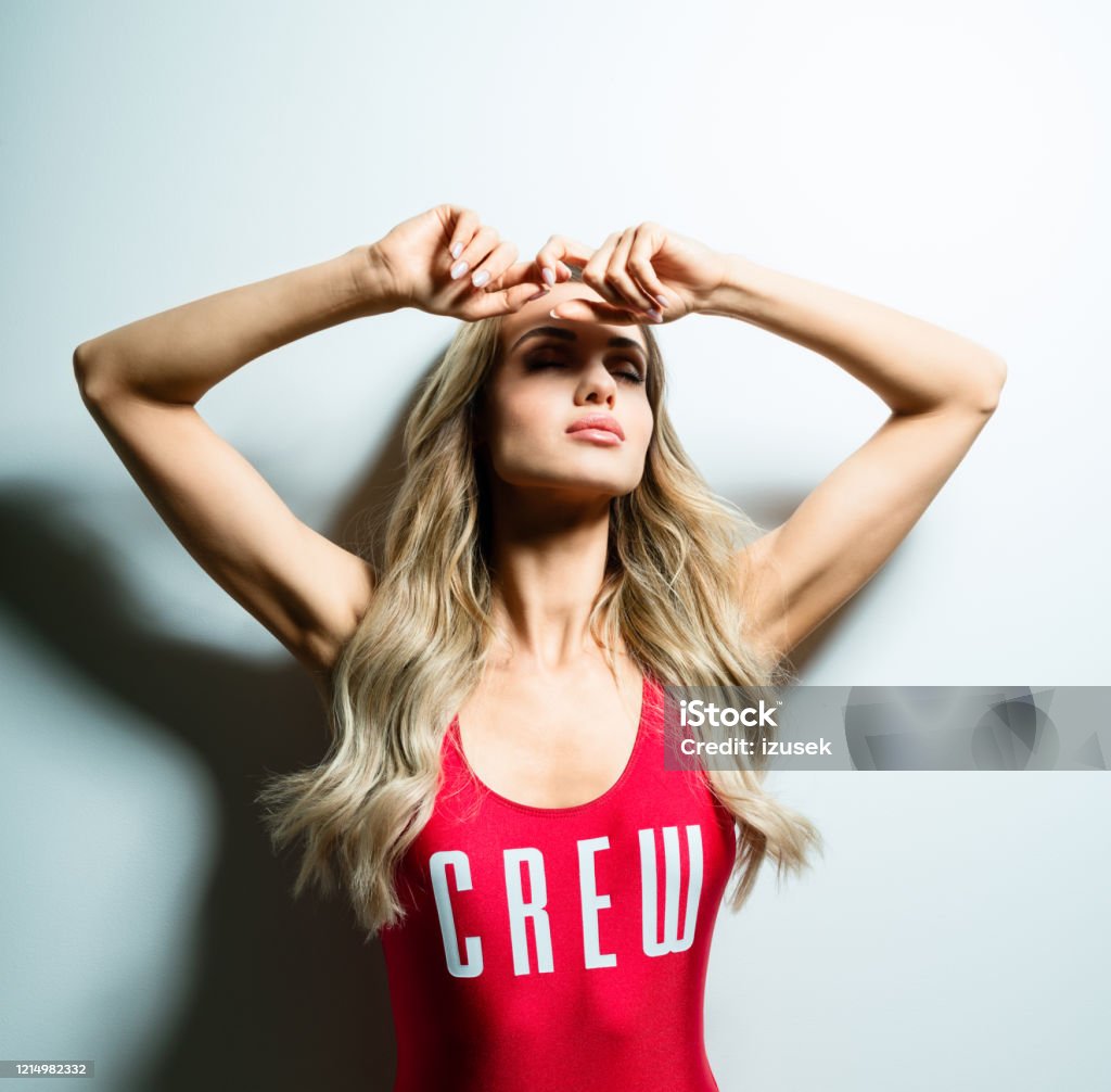 Glamour summer portrait of young woman in red swimsuit Summer portrait of glamour blond long hair young woman wearing red swimsuit. Standing against white background. Studio shot, one person. 25-29 Years Stock Photo